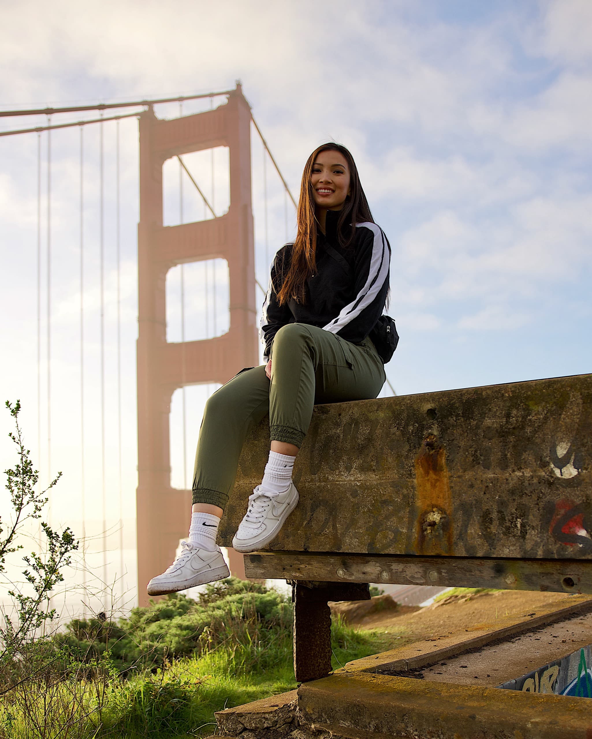 Hoang sitting on a bench in front of the Golden Gate Bridge on a bright day